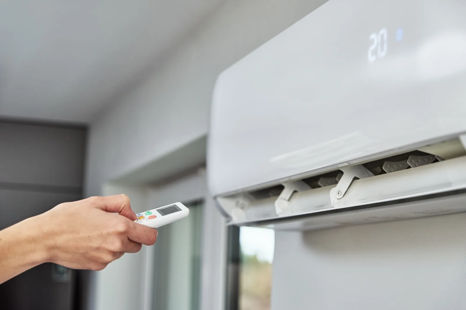 Hand adjusting temperature on air conditioner